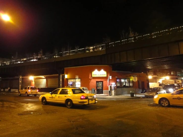 taxi cabs and taxis in front of an overpass at night