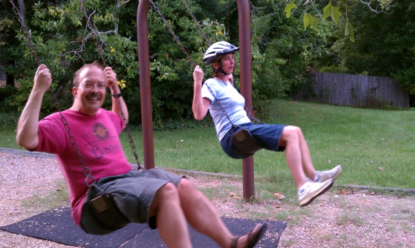 a young man sitting on a swing in a playground