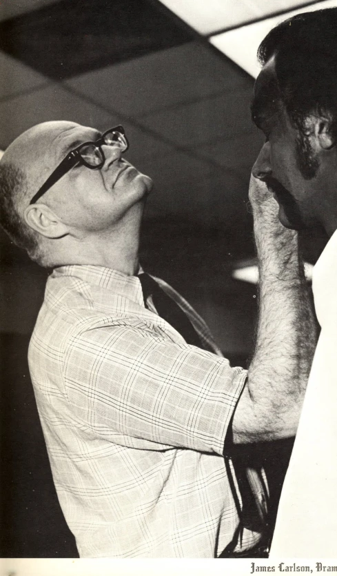 a man standing next to a black cat while looking at soing