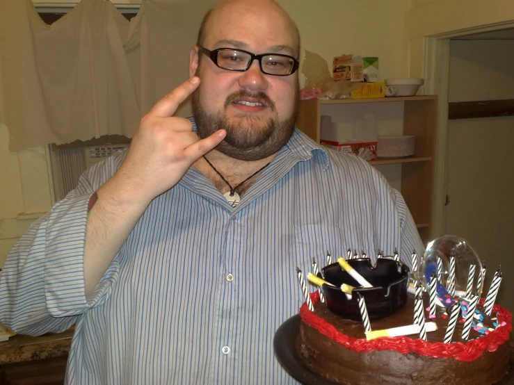 a man that is pointing at soing with a cake