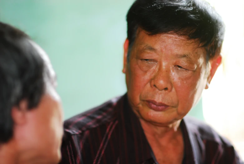 a man in a red striped shirt stares at his reflection