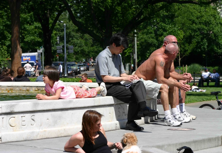 two males sit on stone benches with a small girl and a dog