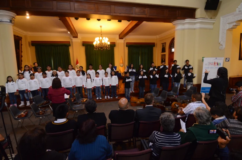 a group of people in white shirts are singing on stage