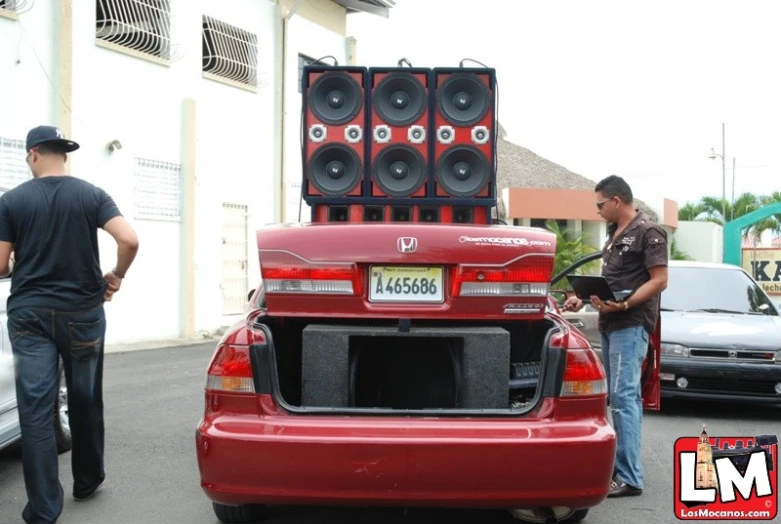 a group of people standing next to a red car