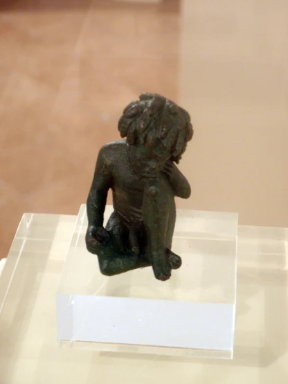 a small brown bronze statue on display in a museum