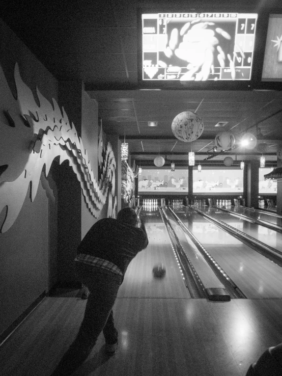 man playing bowling on a television screen in a bowling alley