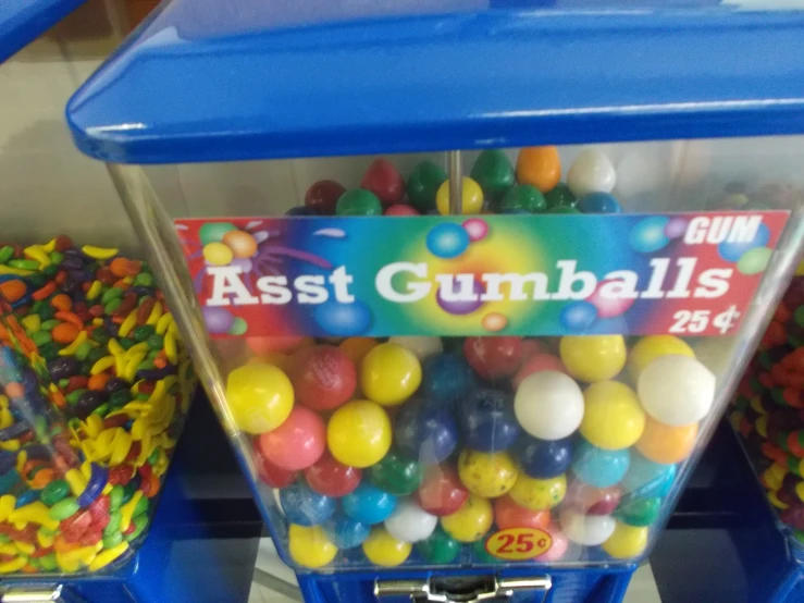 assorted gumballs are piled into a blue bin