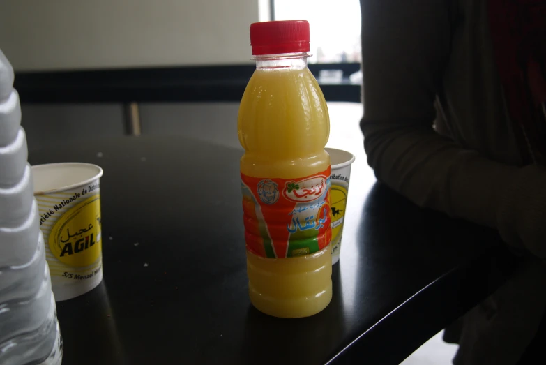 a plastic bottle filled with a lemonade drink next to two cups
