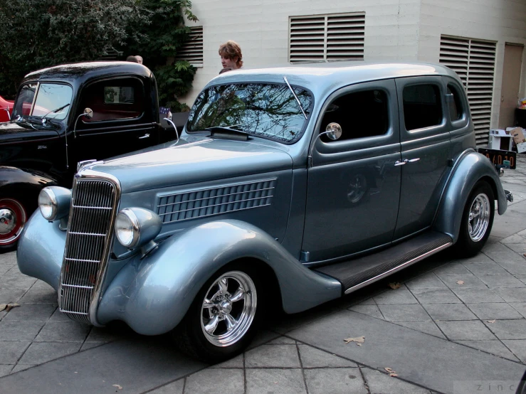 an antique model sedan parked next to another old car