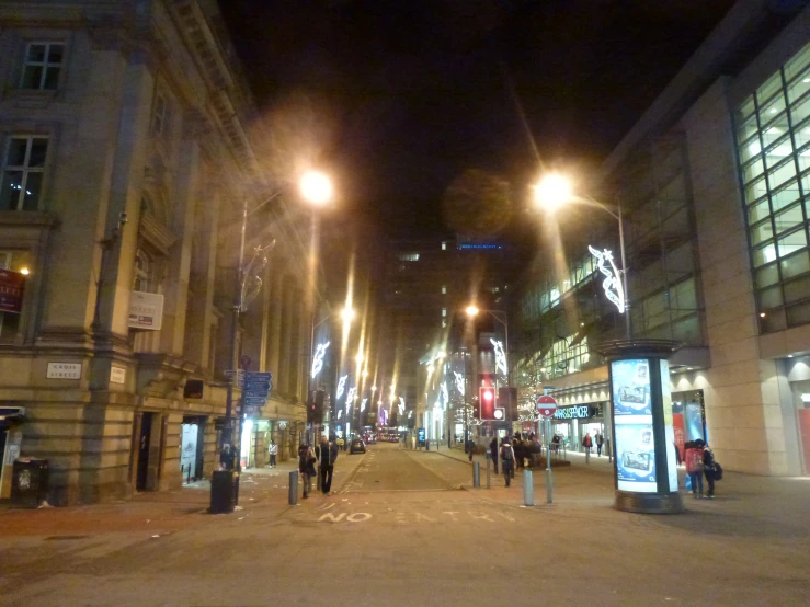 a group of people walking down a street at night