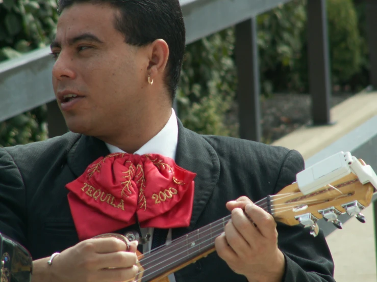 a man holding an electric guitar while wearing a red bow tie