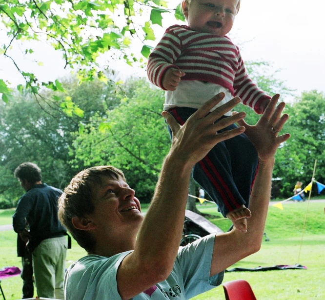 a man holding a small child up to the sky
