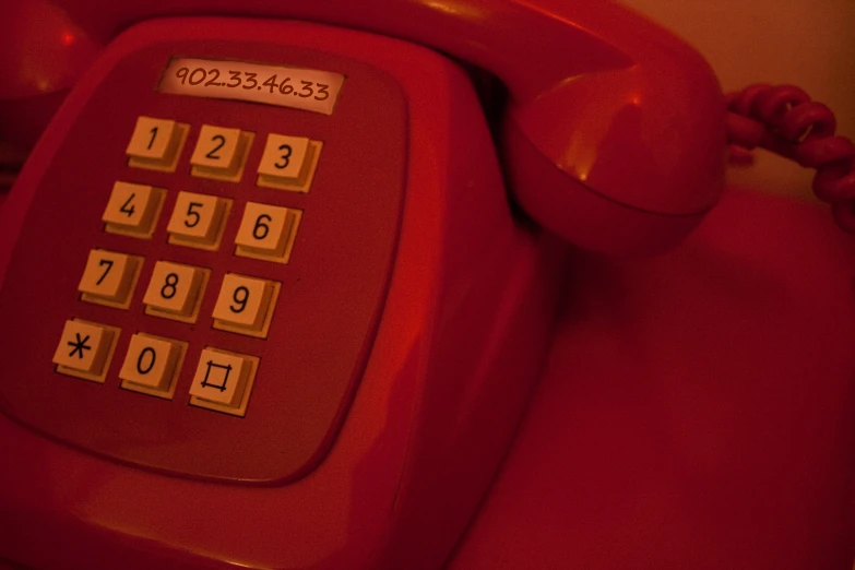 a red rotary rotary telephone with two numbers