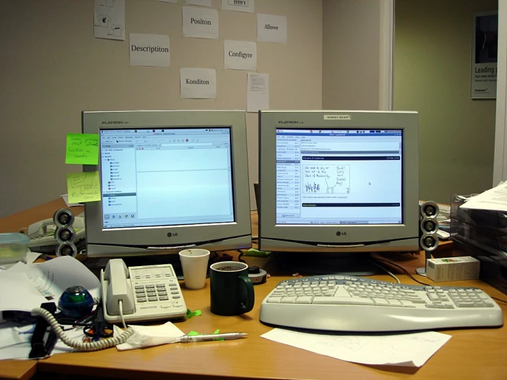two computer monitors sitting on top of a desk