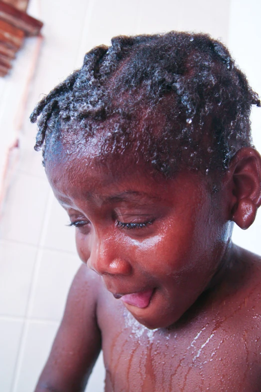 a young child with short hair standing in the water