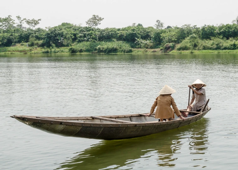 two men sitting in a canoe on a lake