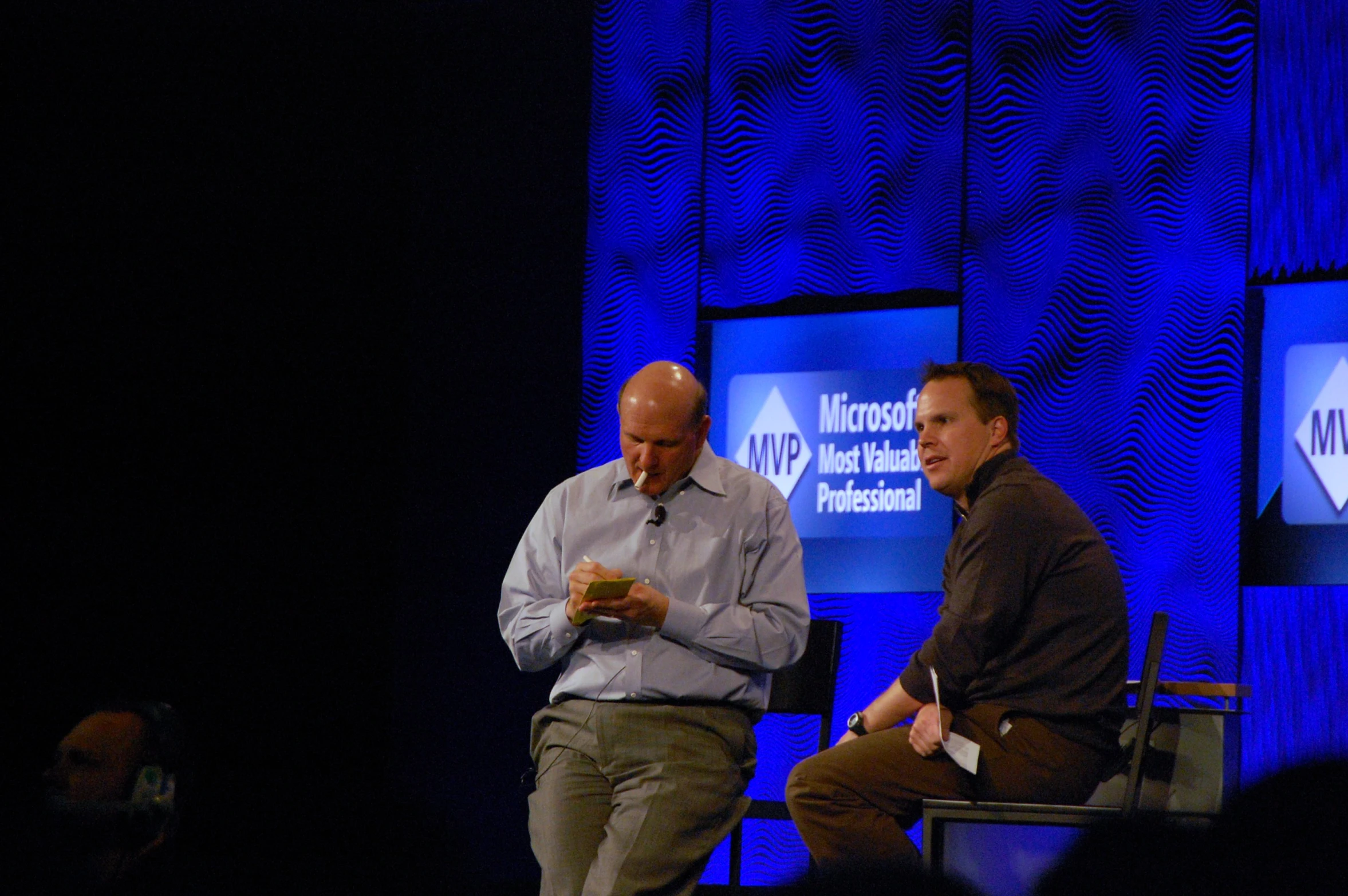 two men talking while holding papers in their hands