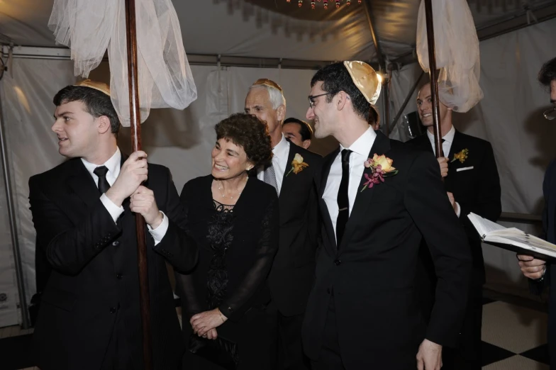 a group of men and women in black suits and tuxedos