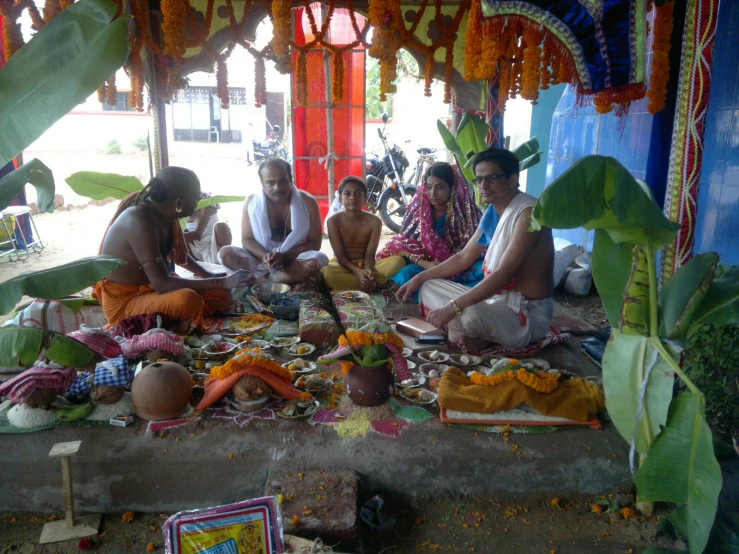 four men are sitting under an outdoor structure