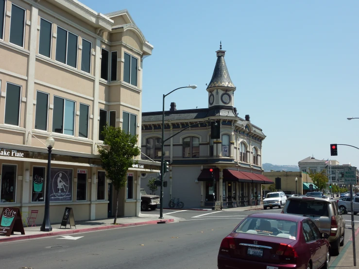 a red car driving down the street with lots of buildings around