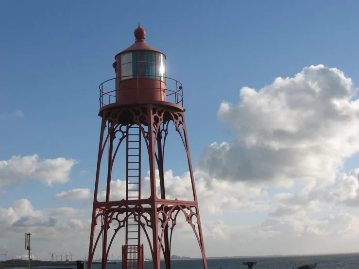 a red lighthouse stands next to some water