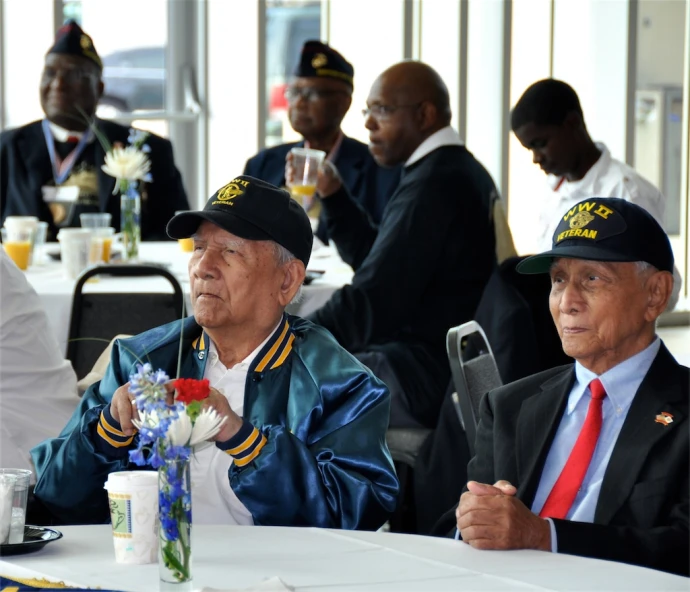 several people in suits and caps are sitting at a table