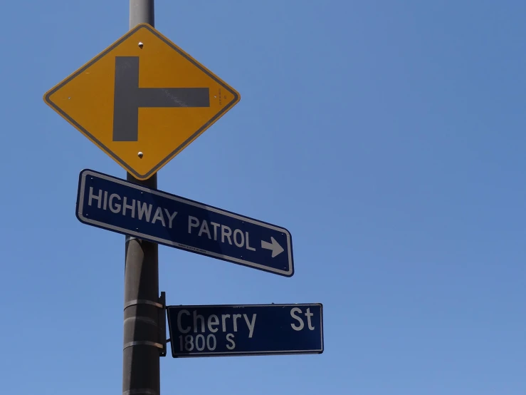 three signs on a metal pole and one is pointing to the left