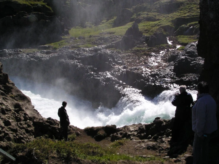 a group of people standing at the edge of a waterfall