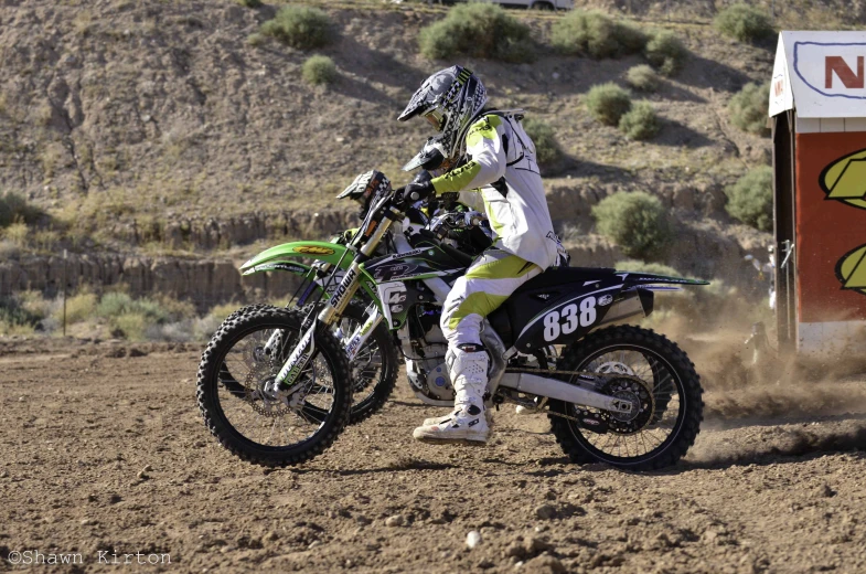 a man riding on the back of a motorcycle through dirt