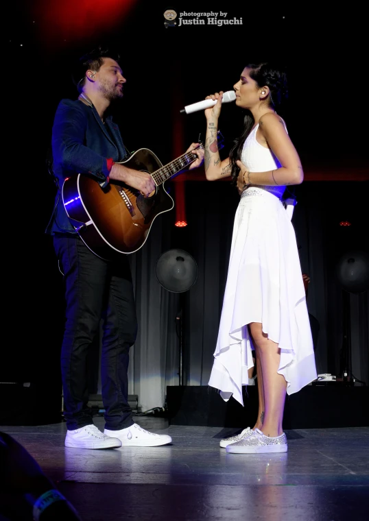 a couple performing on stage with one playing guitar