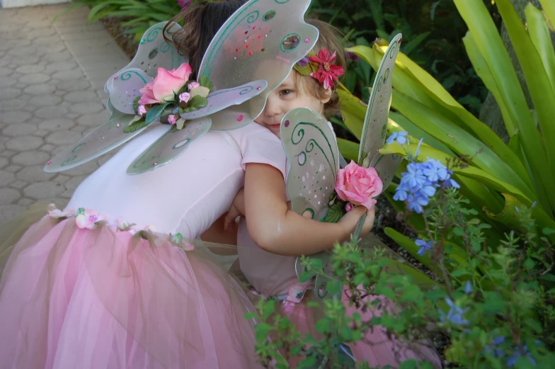 a  dressed in tinkerbell fairy costume with pink flowered bouquet