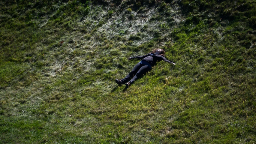 a person in a black shirt laying down on the grass