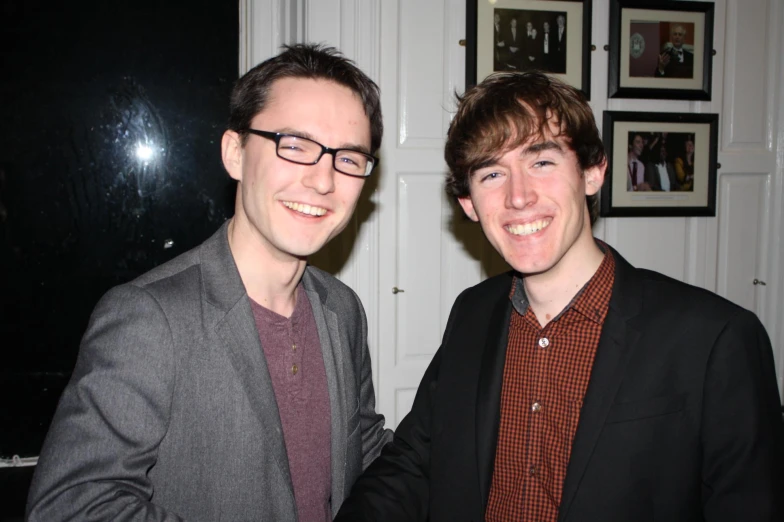 two young men in suits pose for a pograph