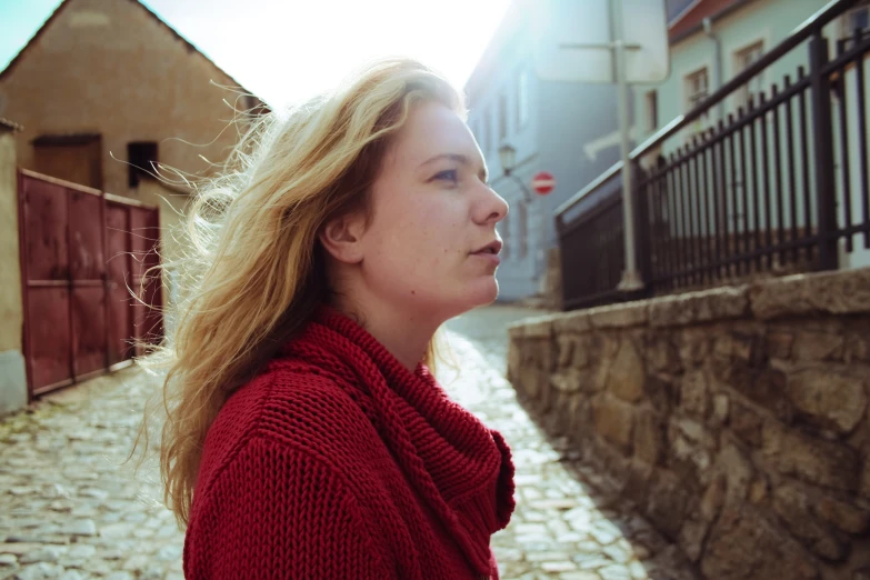 a woman stands in an alley looking away from the camera