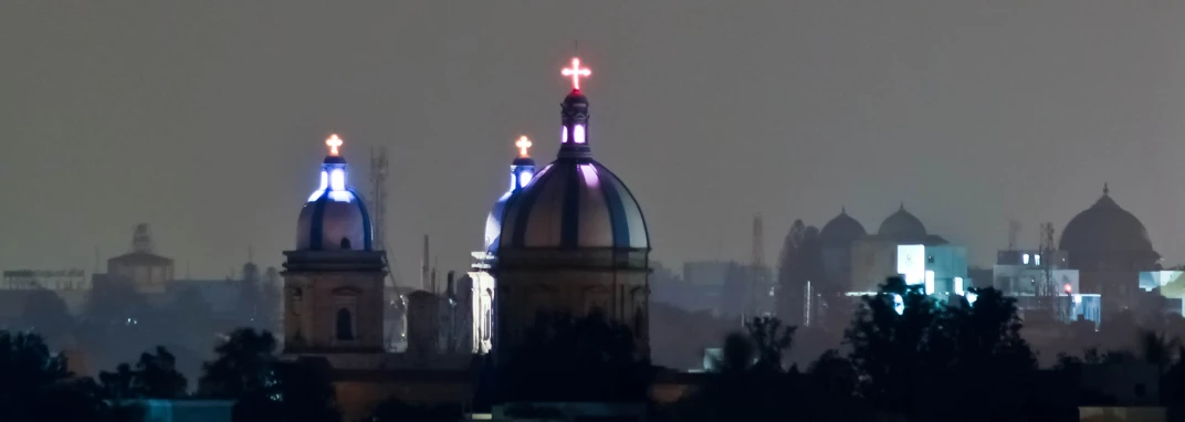 an old building with two dome roofs stands illuminated in night
