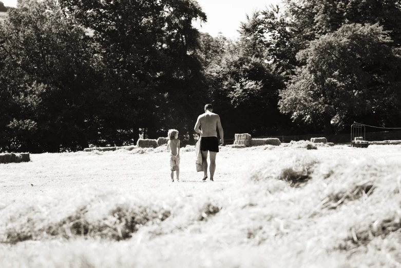 a man walking across a field while holding a small child