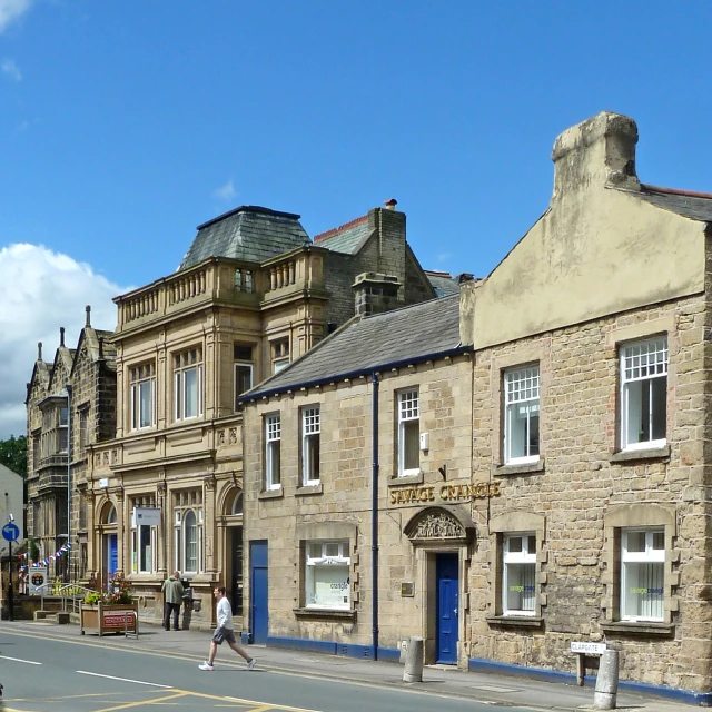 people walk on the street in front of many old brick buildings