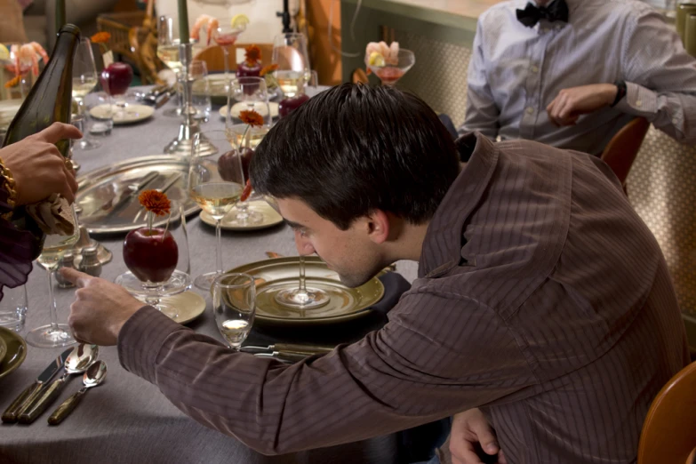 people are sitting at the dinner table with wine glasses