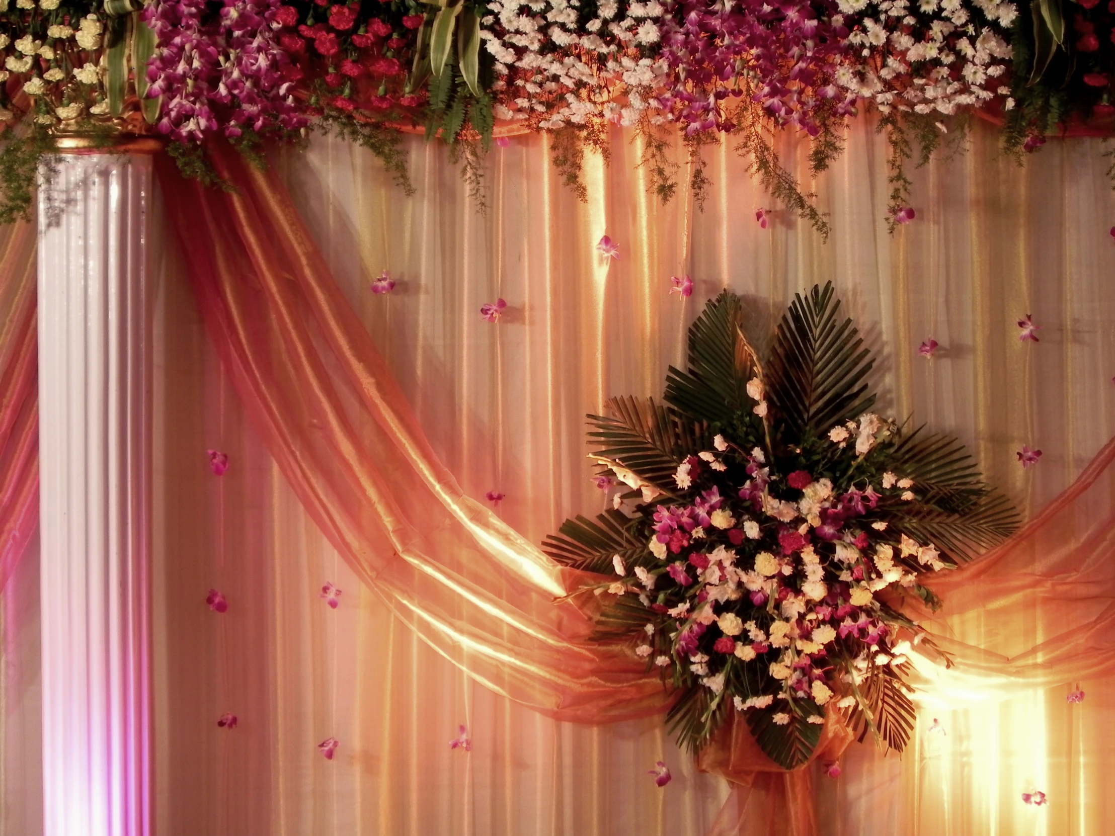 an arrangement of flowers and greenery is decorated with a curtain