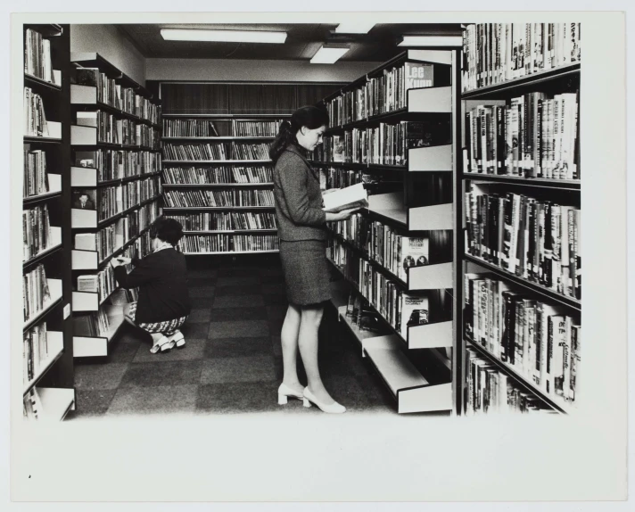 a woman looking at a shelf in a liry with her dog