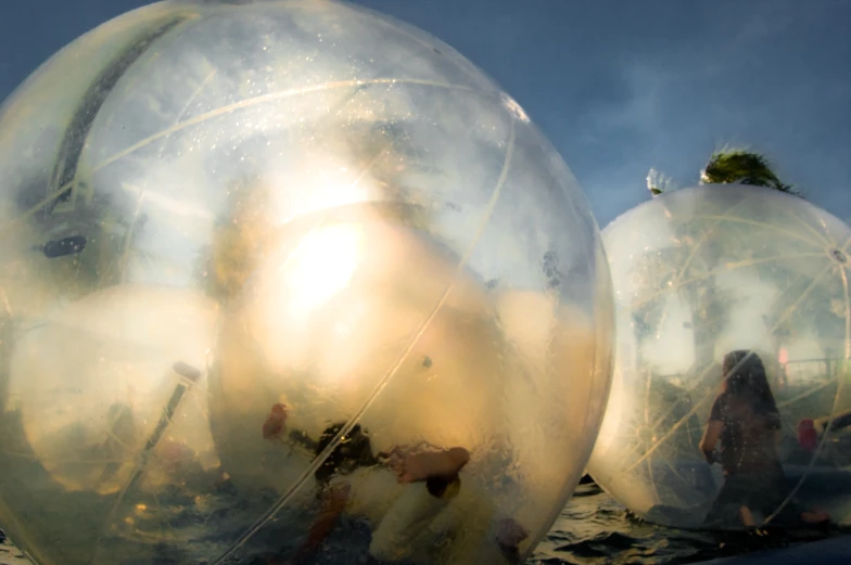 large transparent plastic balls in the ocean next to each other