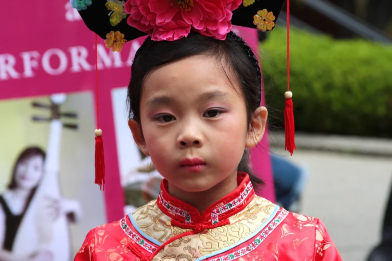 an asian girl in red and gold with a flower on her head