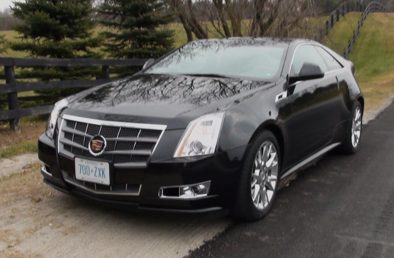 a black cadillac is parked in the side of a road