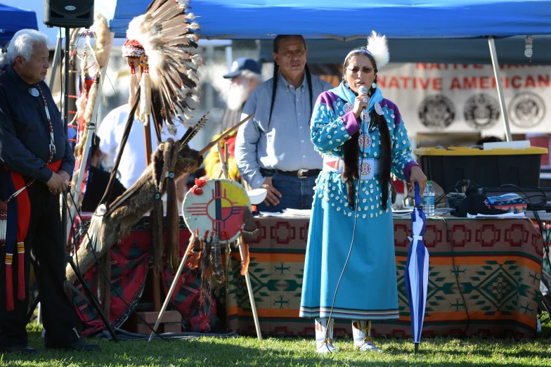 the native woman is singing to people at a native american festival