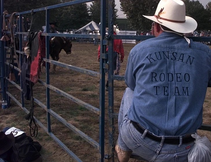 a man with cowboy hat looking over the gate