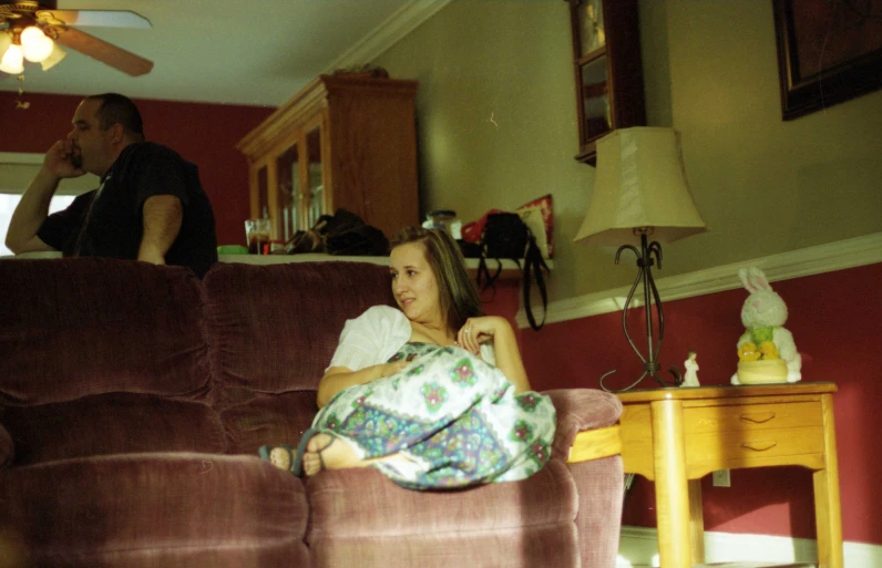 two people in living room with one person staring at soing