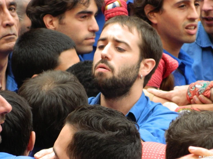 a man wearing a blue shirt surrounded by other men