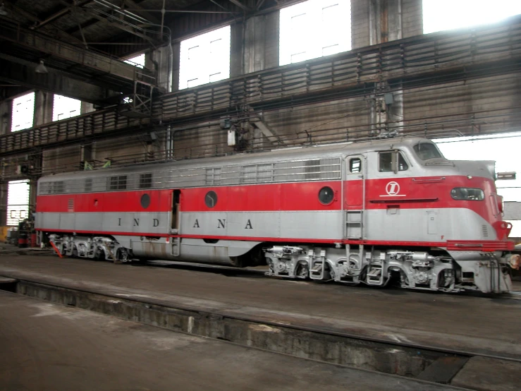 red and white train car parked in a large warehouse