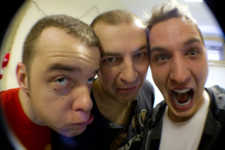 three young men making faces with a reflection in a mirror