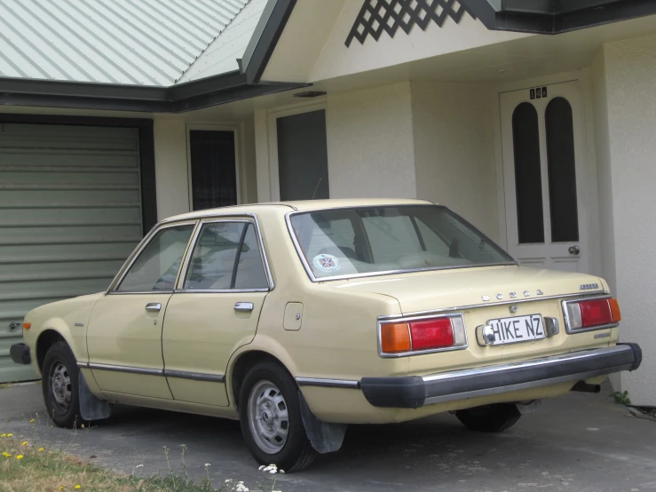 a beige car sits parked next to the house